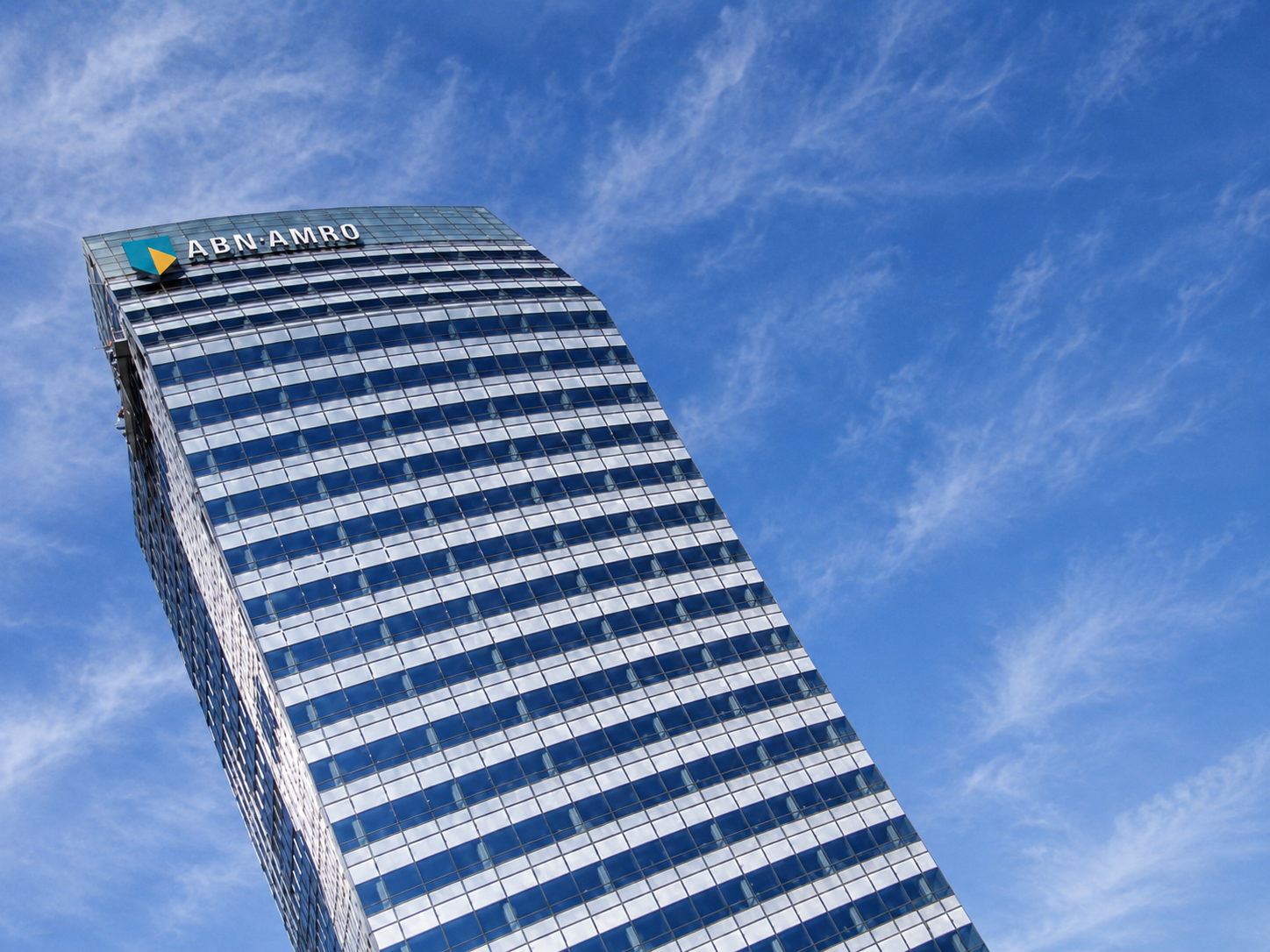 Moderne kantoortoren tegen een blauwe lucht met bewolking